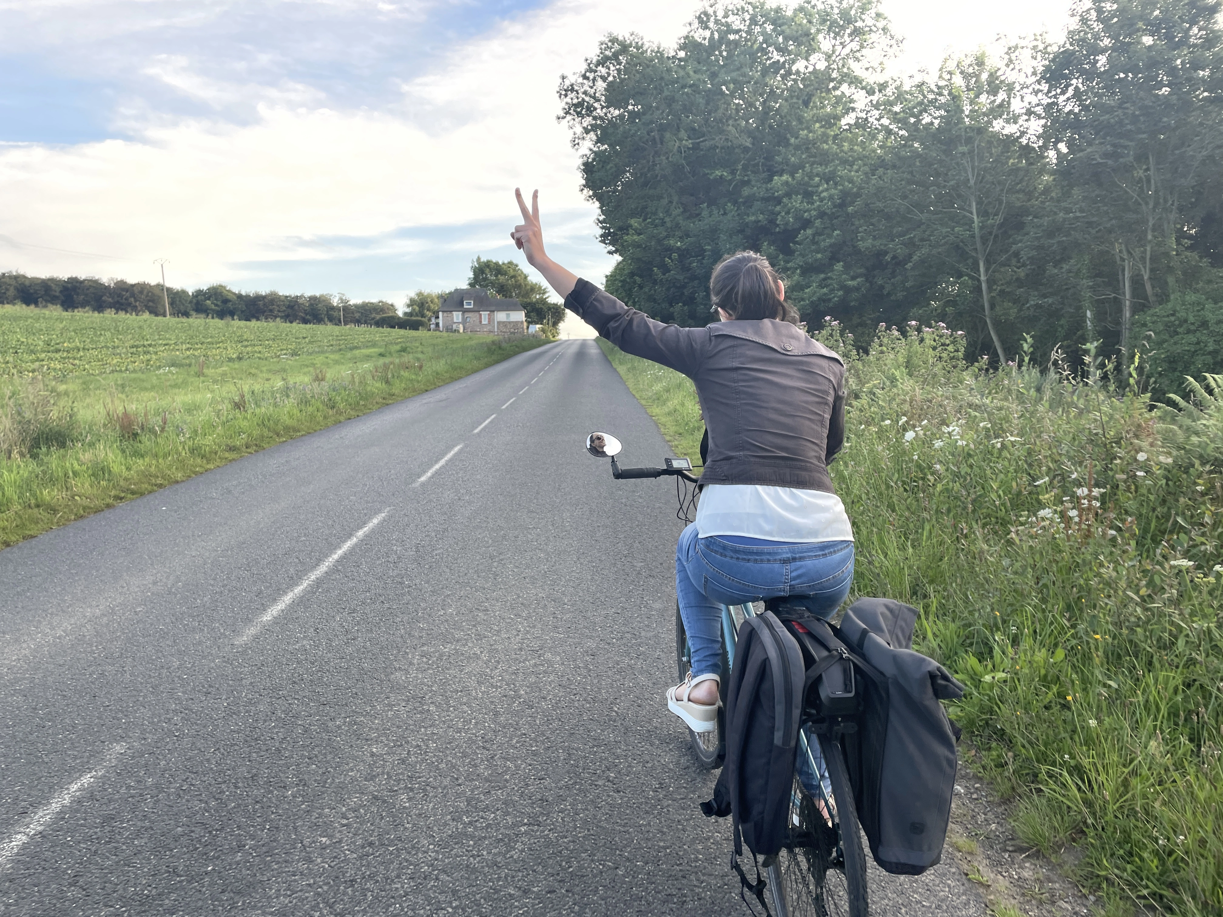 Photo d'une cycliste abordant une côte avec deux doigts levé en V en signe de facilité